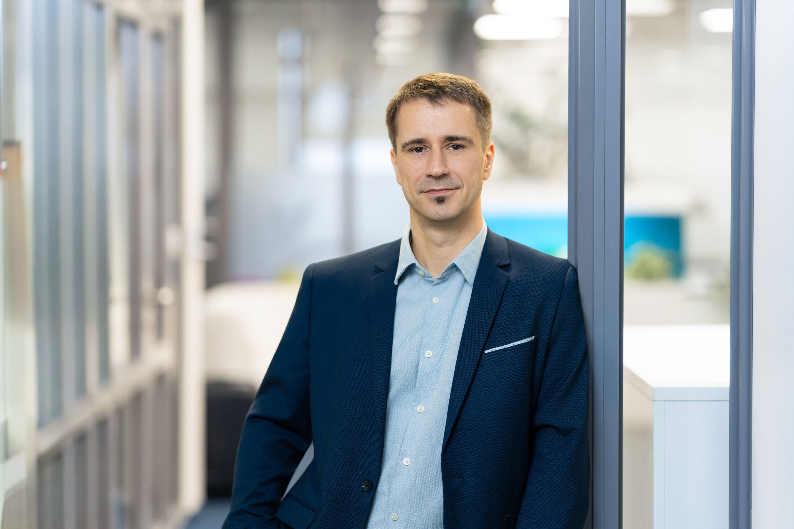 Zigmars Lacis, Group CFO of Hive Finance Group, standing by a glass partition in the office.
